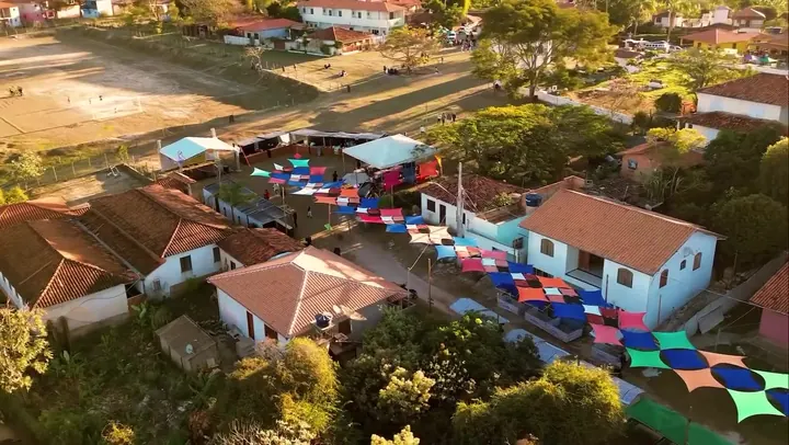 Vista aérea de Milho Verde: casas de telhado colonial e a rua coberta de bandeirinhas coloridas