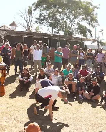 Roda de capoeira ao ar livre, com o público sentado em volta
